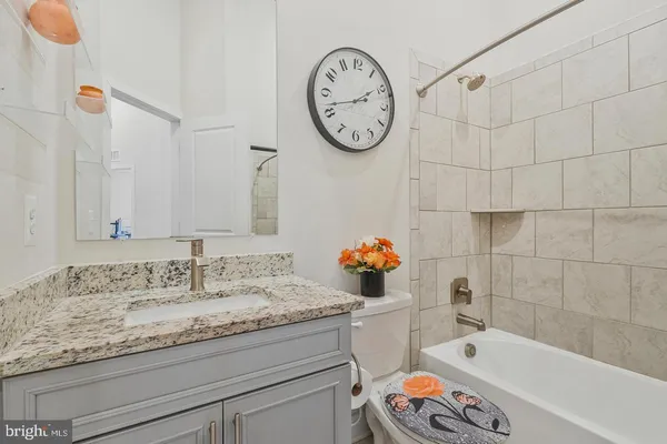 a bathroom with a granite countertop sink mirror vanity and bathtub
