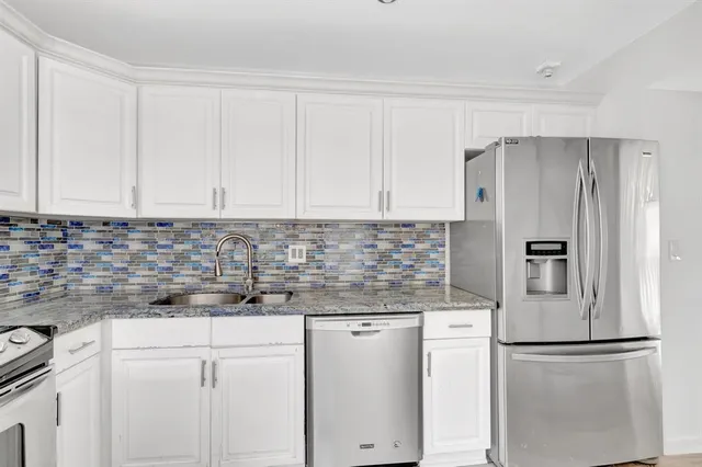 a kitchen with stainless steel appliances white cabinets and a refrigerator