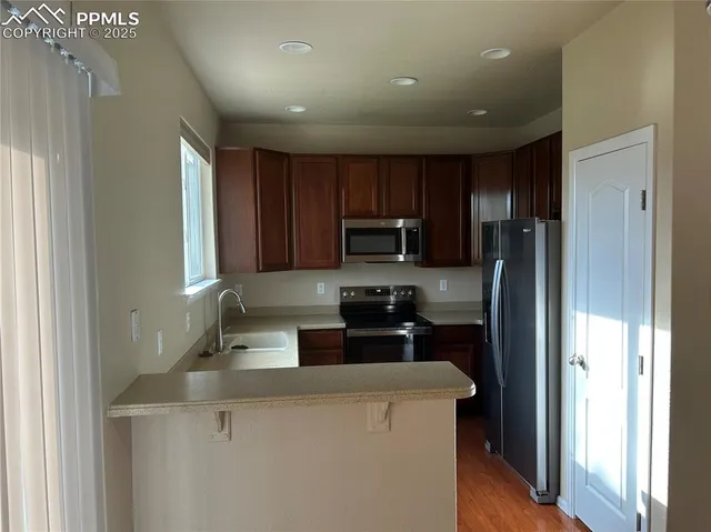 a kitchen with a refrigerator a stove top oven a sink and dishwasher with wooden floor