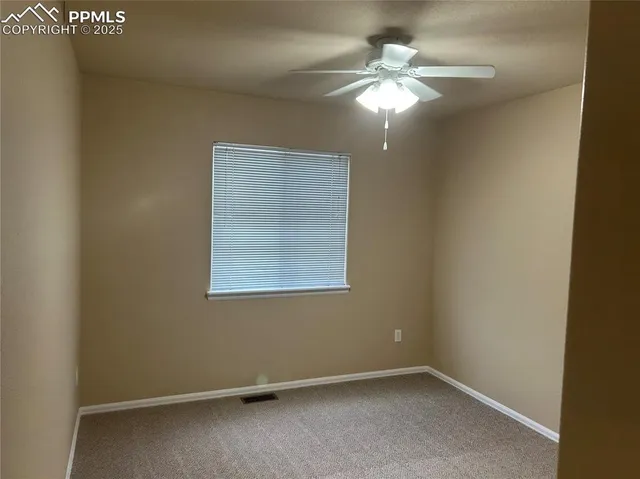 an empty room with a window and a chandelier fan
