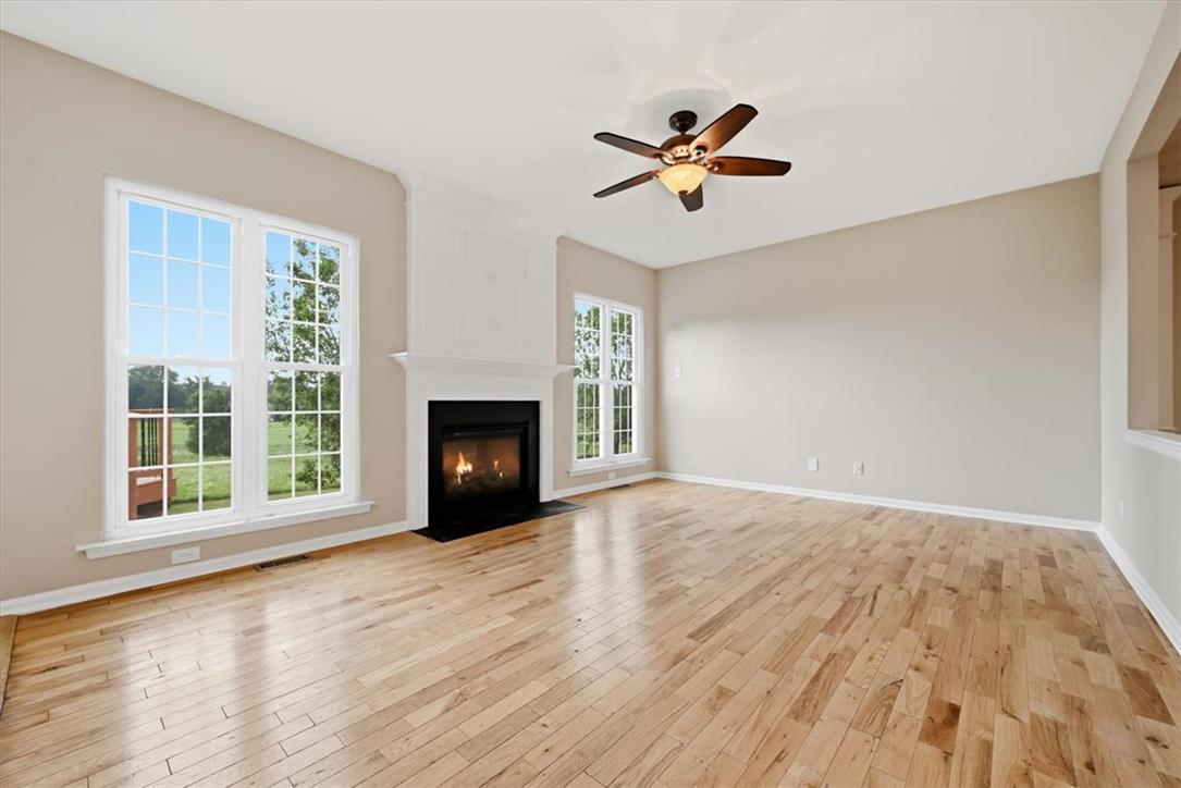 8761 Cascade Road Breinigsville, PA 18031 - Photo 43 of 84 A welcoming living area showcases a glowing fireplace, pristine hardwood flooring, and abundant natural light from large windows.