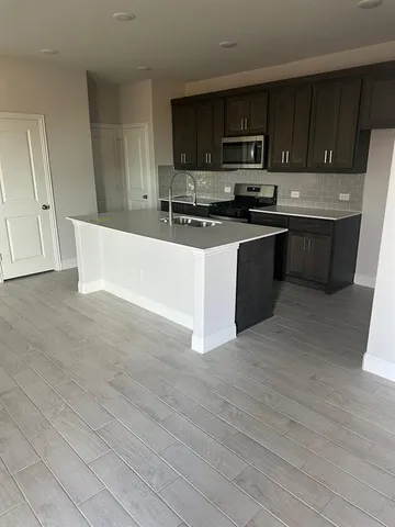 a kitchen with stainless steel appliances a stove a sink a microwave and wooden cabinets