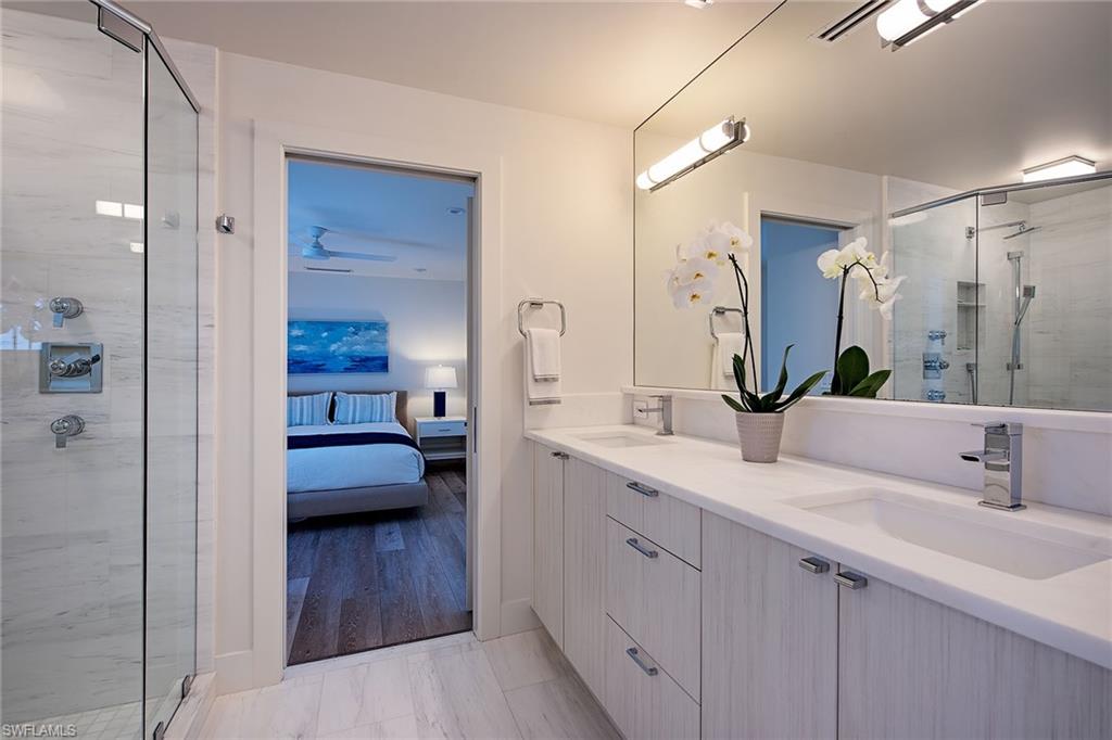 1600 Murex Lane Naples, FL 34102 - Photo 16 of 25 a en suite bathroom with a sink a large mirror and shower