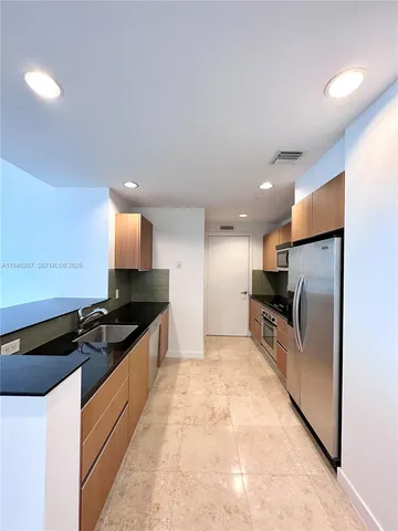 a kitchen with stainless steel appliances kitchen island granite countertop a refrigerator and a sink