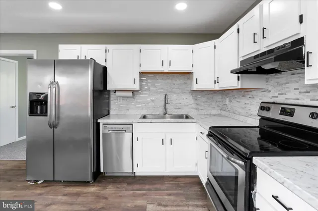 a kitchen with stainless steel appliances granite countertop white cabinets a refrigerator a stove a sink and dishwasher