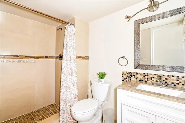 a bathroom with a sink a toilet a mirror and shower