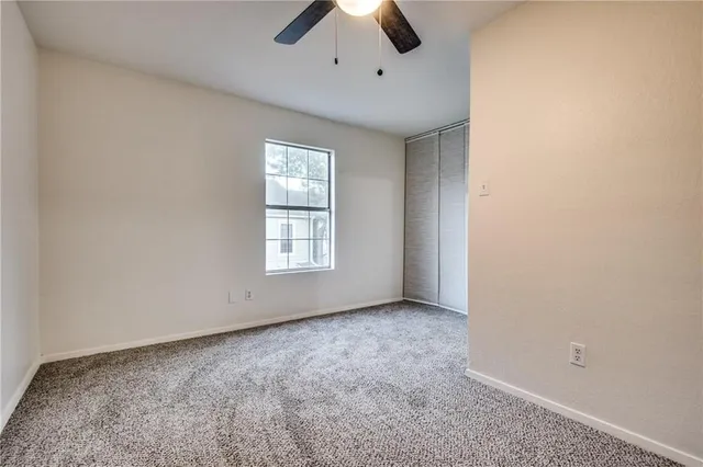 an empty room with a ceiling fan and window