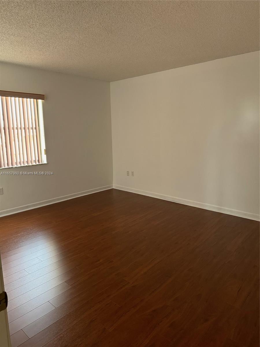 10253 Northwest 9th St Circle, Unit 4076 Miami, FL 33172 - Photo 4 of 11 an empty room with wooden floor and windows