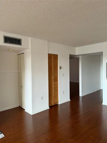 an empty room with wooden floor and closet area