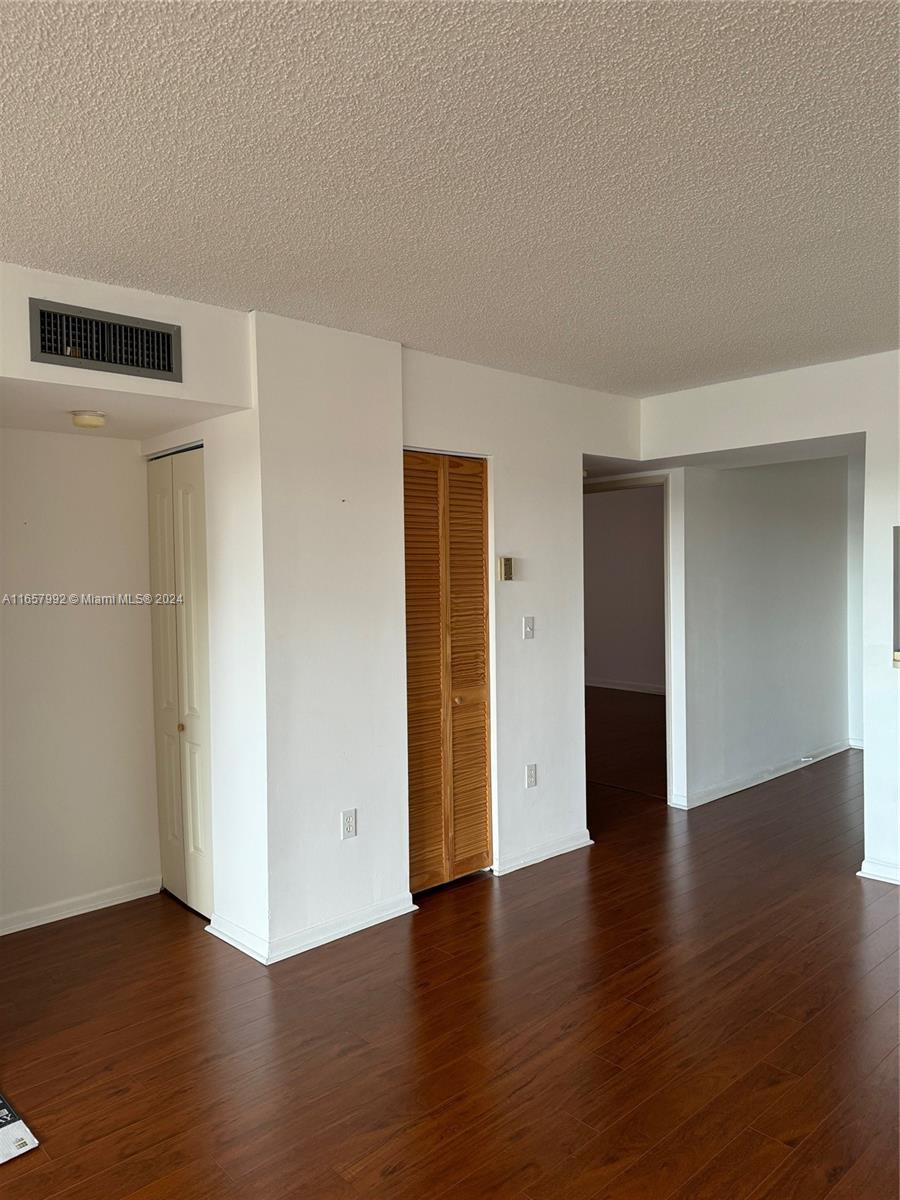 10253 Northwest 9th St Circle, Unit 4076 Miami, FL 33172 - Photo 8 of 11 an empty room with wooden floor and closet area