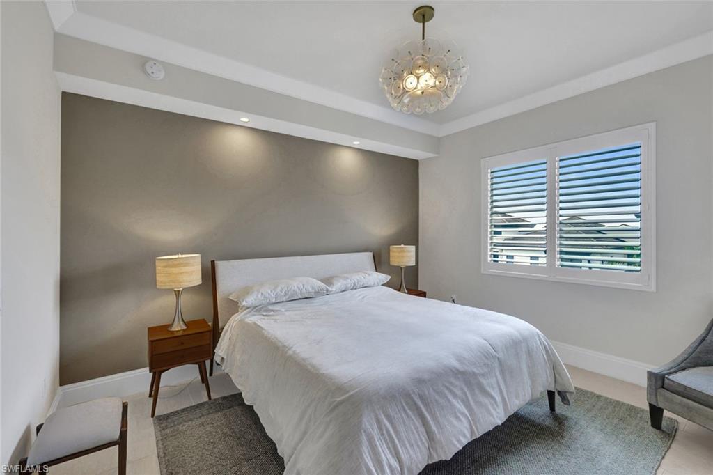 1035 3rd Avenue South, Unit 514 Naples, FL 34102 - Photo 16 of 35 a bedroom with a bed and a chandelier