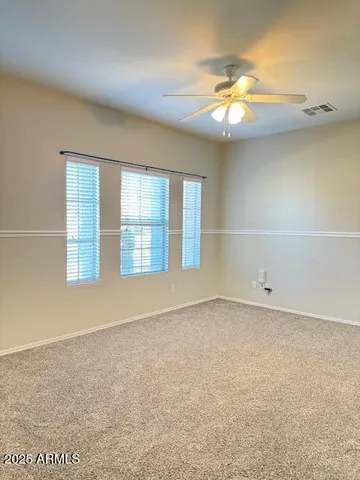 an empty room with a chandelier fan and windows
