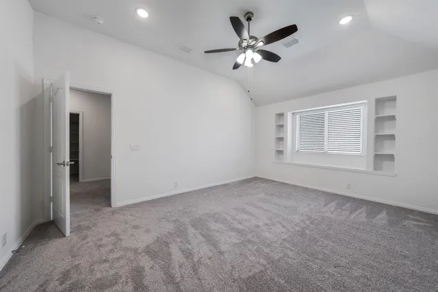 an empty room with a chandelier fan and windows