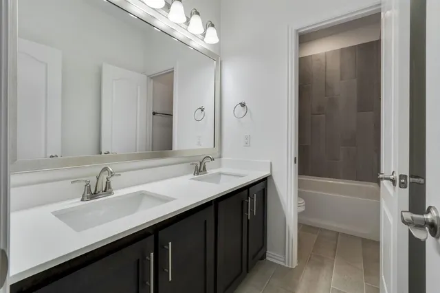 a bathroom with a double vanity sink a tub and a mirror