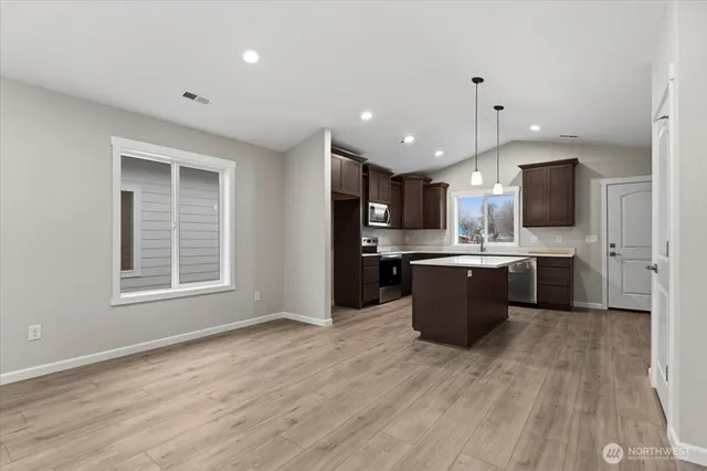 a kitchen with a sink a center island a stove cabinets and a counter top space