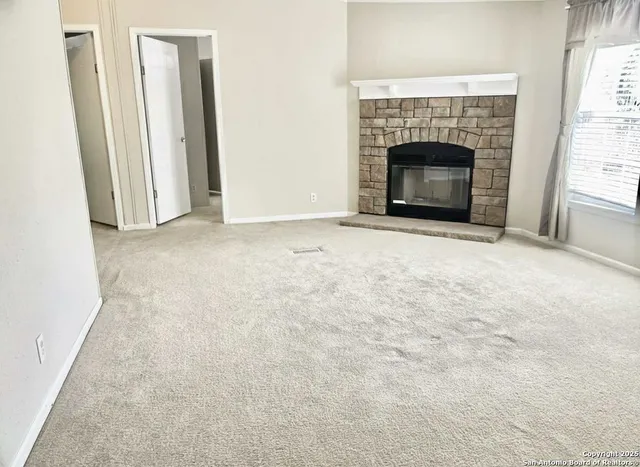 an empty room with a fireplace and window