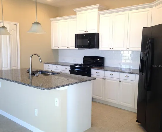 a kitchen with stainless steel appliances granite countertop a refrigerator stove a sink dishwasher and white cabinets with wooden floor