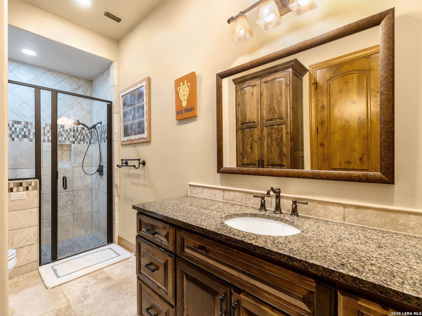 14454 Santa Rita Helotes, TX 78023 - Photo 39 of 70 a bathroom with a granite countertop sink a mirror and a shower