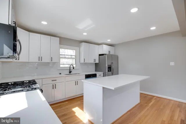 a kitchen with a sink a stove a refrigerator and white cabinets