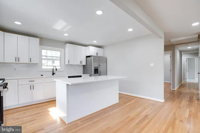 a kitchen with white cabinets and wooden floor