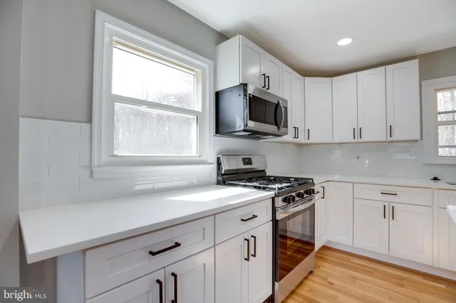 a kitchen with stainless steel appliances white cabinets and a stove top oven