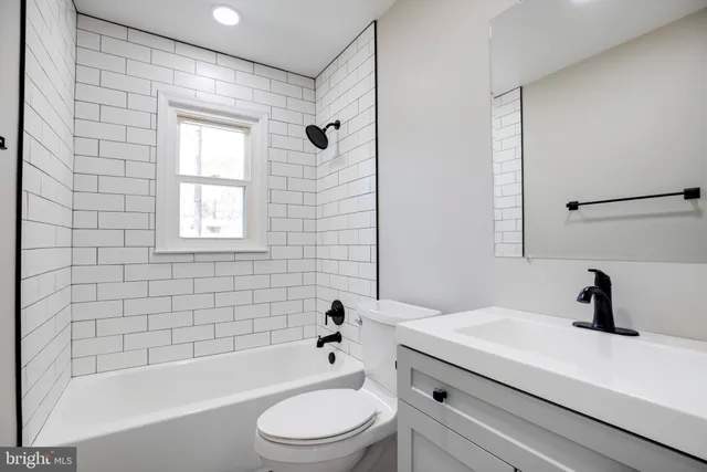 a bathroom with a bathtub shower sink vanity mirror and toilet