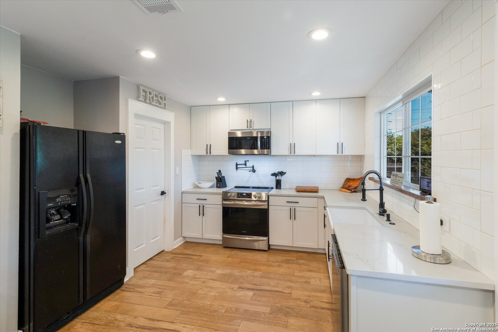 9210 Cedar Point Helotes, TX 78023 - Photo 9 of 22 a kitchen with a sink a refrigerator and a stove top oven