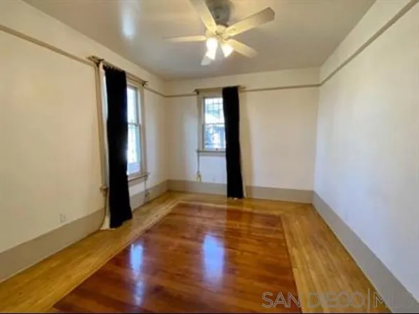 a view of an empty room with window and wooden floor