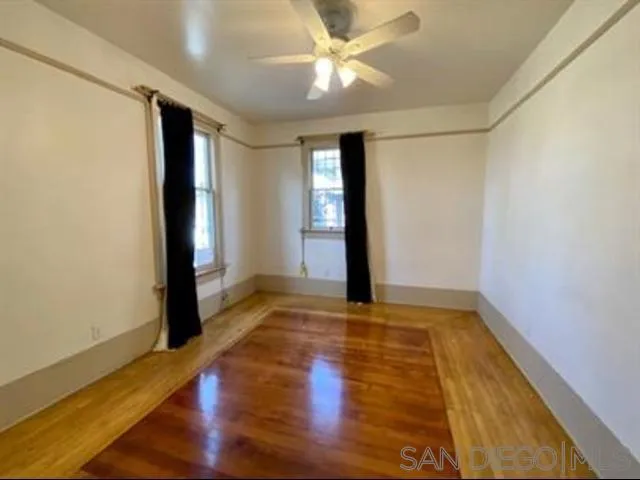a view of an empty room with window and wooden floor