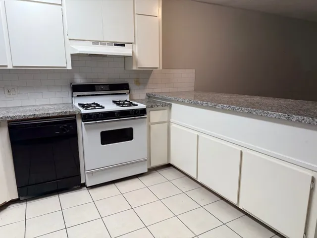 a kitchen with white cabinets and appliances