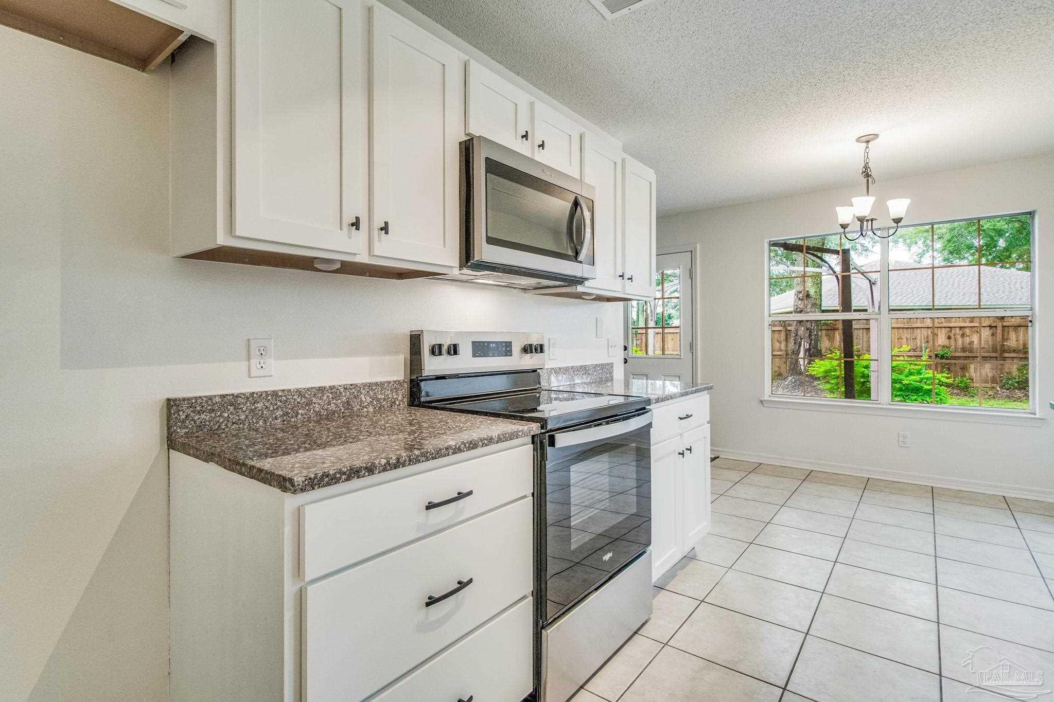 4737 Frontier Road Pace, FL 32571 - Photo 12 of 32 a kitchen with stainless steel appliances granite countertop a stove a sink and a microwave