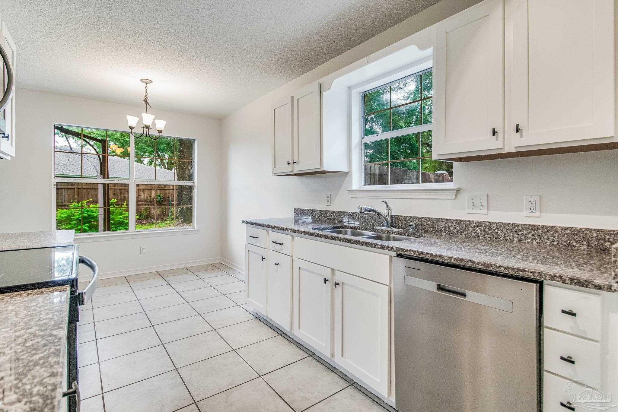 4737 Frontier Road Pace, FL 32571 - Photo 13 of 32 a kitchen with a sink window and cabinets