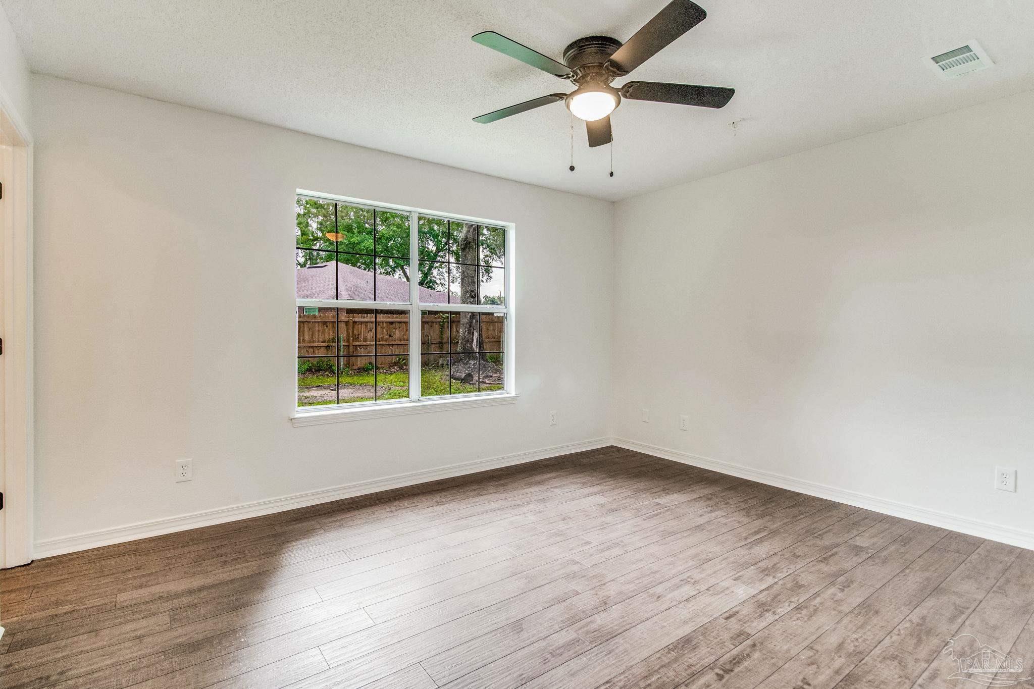 4737 Frontier Road Pace, FL 32571 - Photo 16 of 32 an empty room with wooden floor and windows