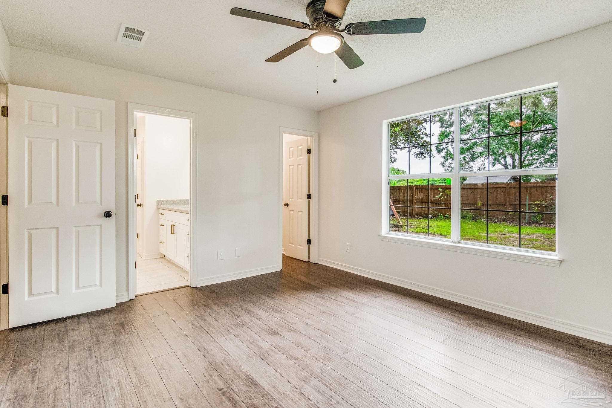 4737 Frontier Road Pace, FL 32571 - Photo 17 of 32 an empty room with wooden floor fan and windows
