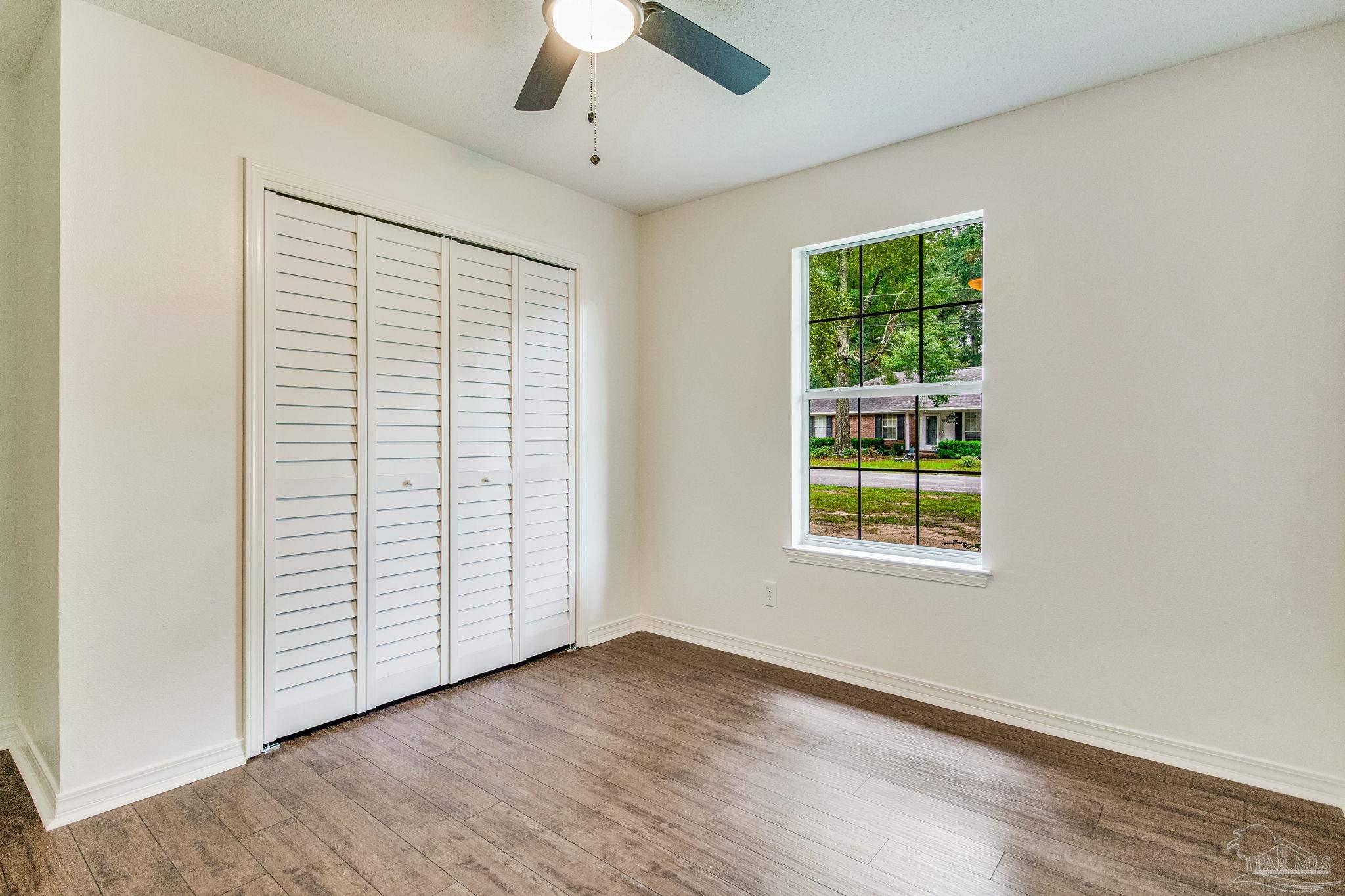 4737 Frontier Road Pace, FL 32571 - Photo 27 of 32 an empty room with wooden floor chandelier fan and windows