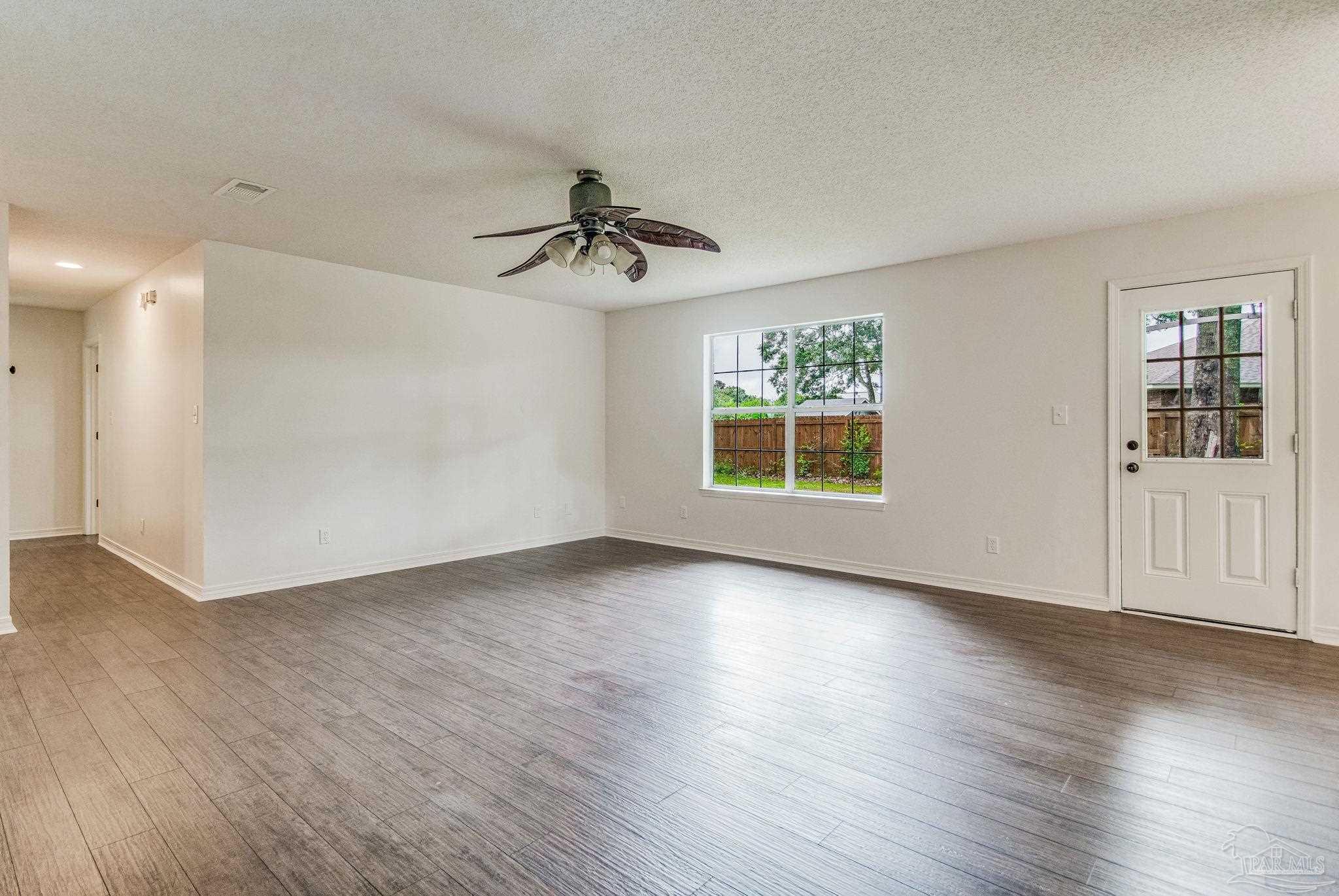4737 Frontier Road Pace, FL 32571 - Photo 6 of 32 a view of an empty room with a window and wooden floor