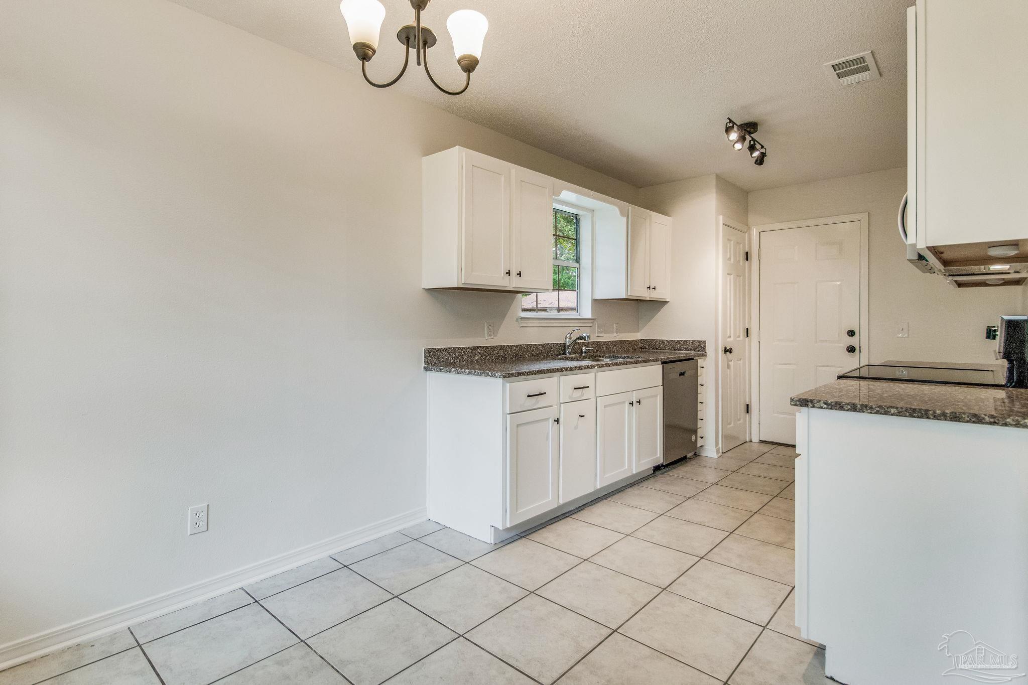 4737 Frontier Road Pace, FL 32571 - Photo 8 of 32 a kitchen with granite countertop white cabinets and white appliances