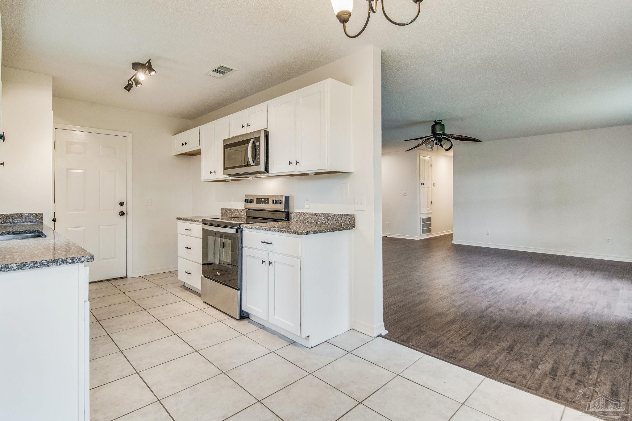 4737 Frontier Road Pace, FL 32571 - Photo 9 of 32 a kitchen with granite countertop white cabinets and stainless steel appliances