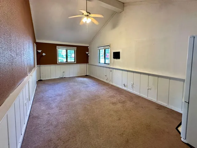 a view of an empty room with a window and a kitchen