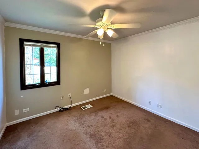 an empty room with a chandelier fan and windows