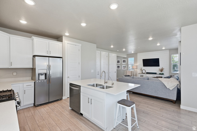 3244 West 1670th Street North Provo, UT 84601 - Photo 15 of 56 Open-concept design featuring a kitchen with white cabinetry, stainless steel appliances, and a central island with a double sink