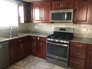 3347 Thornberry Lane Glenview, IL 60025 - Photo 5 of 12 a kitchen with stainless steel appliances granite countertop wooden cabinets and a stove top oven