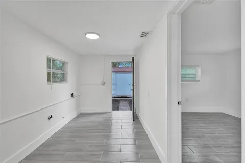 a view of an empty room with wooden floor and a bathroom