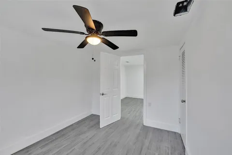 an empty room with wooden floor cabinet and ceiling fan