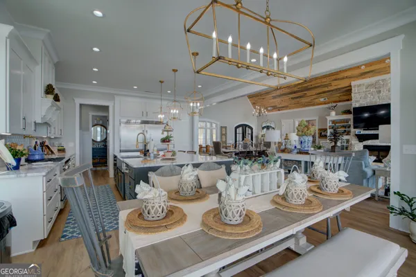 a dining room with wooden floor a chandelier a wooden table and chairs