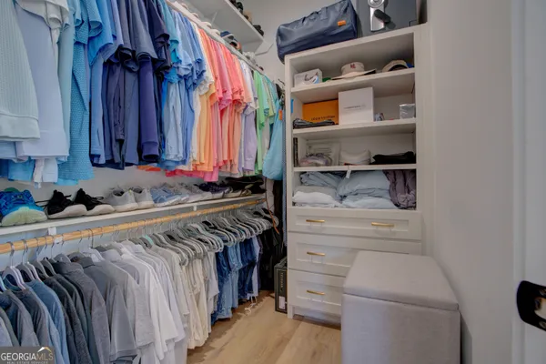 a view of walk in closet with clothes and shoes