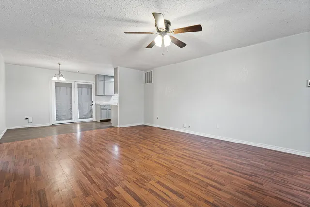 a view of empty room with wooden floor and ceiling fan