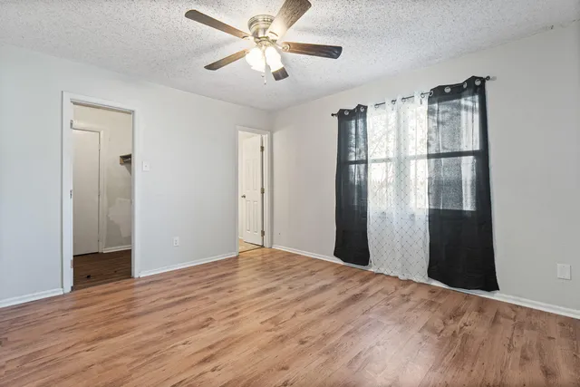 a view of a big room with wooden floor and a chandelier fan