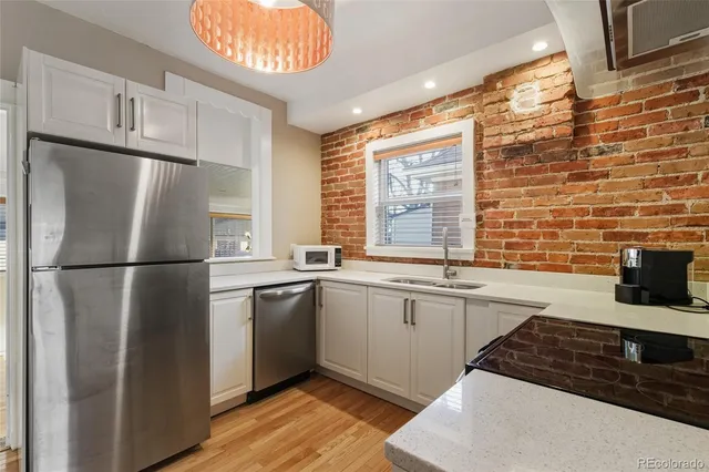 a kitchen with stainless steel appliances granite countertop a refrigerator a sink dishwasher a stove and a refrigerator