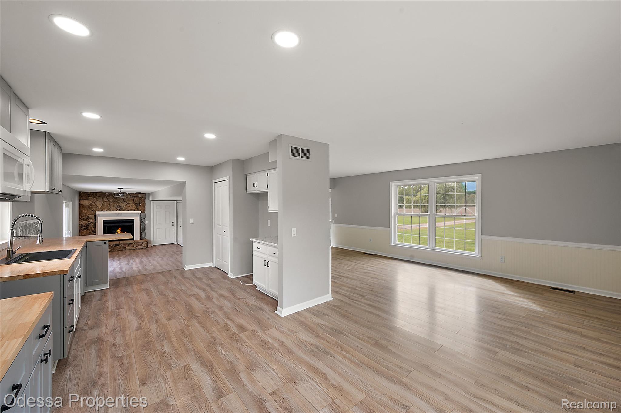 1442 Riley Center Road Memphis, MI 48041 - Photo 21 of 62 Unfurnished living room with a fireplace, light wood-style floors, recessed lighting, and wainscoting